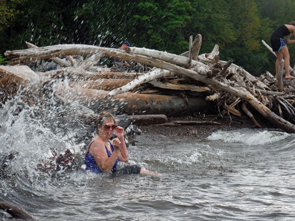 The waves are splashing against the logs and Karen.